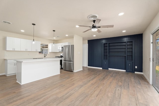 kitchen featuring white cabinets, a kitchen island, decorative light fixtures, stainless steel appliances, and light wood-type flooring