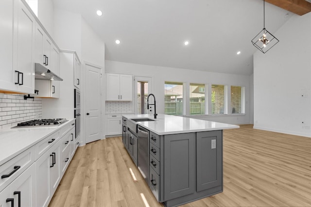 kitchen with gray cabinets, a kitchen island with sink, white cabinets, and stainless steel appliances