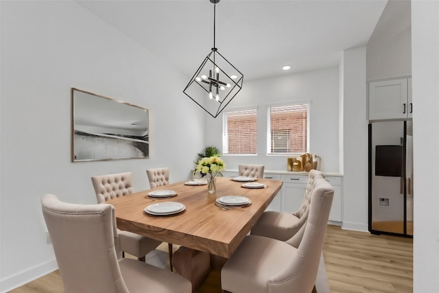 dining area with light hardwood / wood-style floors and an inviting chandelier