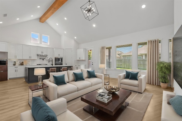 living room with sink, high vaulted ceiling, a notable chandelier, light hardwood / wood-style floors, and beamed ceiling