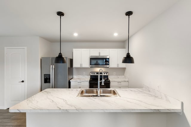 kitchen featuring white cabinetry, hanging light fixtures, appliances with stainless steel finishes, and kitchen peninsula