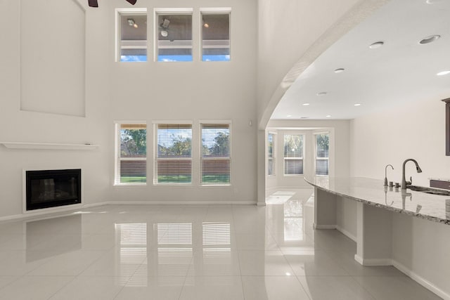 unfurnished living room featuring sink, light tile patterned floors, and plenty of natural light