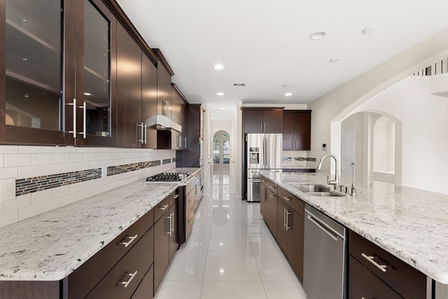 kitchen with sink, an island with sink, decorative backsplash, and appliances with stainless steel finishes