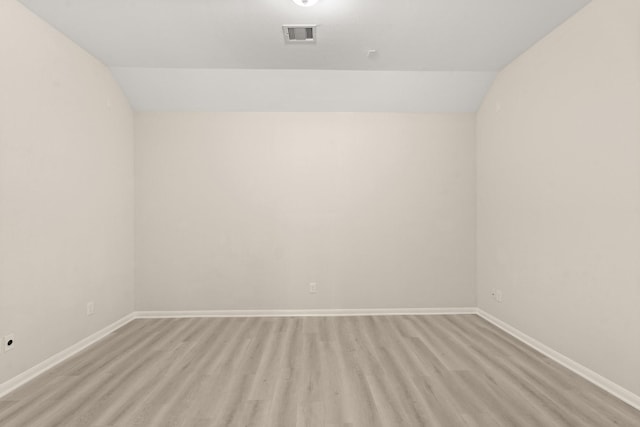 empty room with light hardwood / wood-style flooring and vaulted ceiling