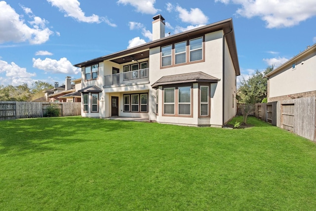 rear view of house featuring a balcony and a lawn