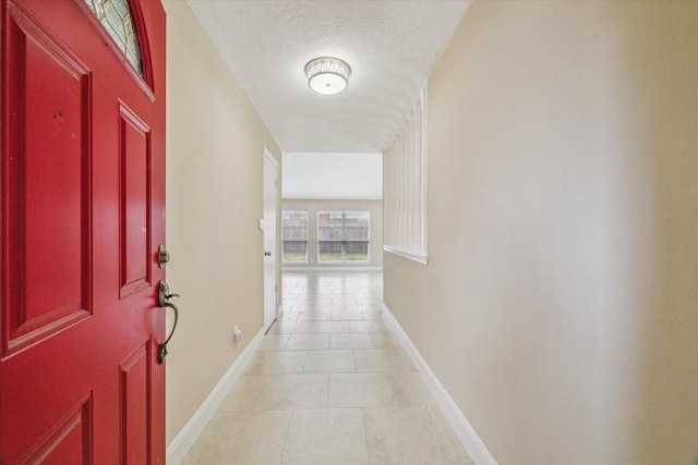 hallway with light tile patterned flooring and a textured ceiling