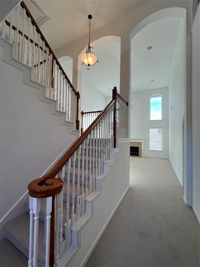 6731 Pinetop Glen Ln, Spring, TX 77379 - staircase featuring arched walkways, carpet, baseboards, and a tile fireplace