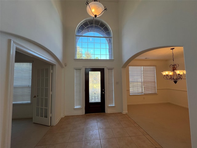 tiled foyer entrance with a towering ceiling and a chandelier