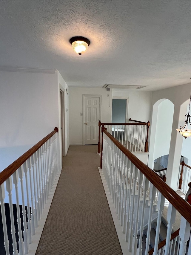6731 Pinetop Glen Ln, Spring, TX 77379 - hallway with a textured ceiling, light carpet, a chandelier, and arched walkways