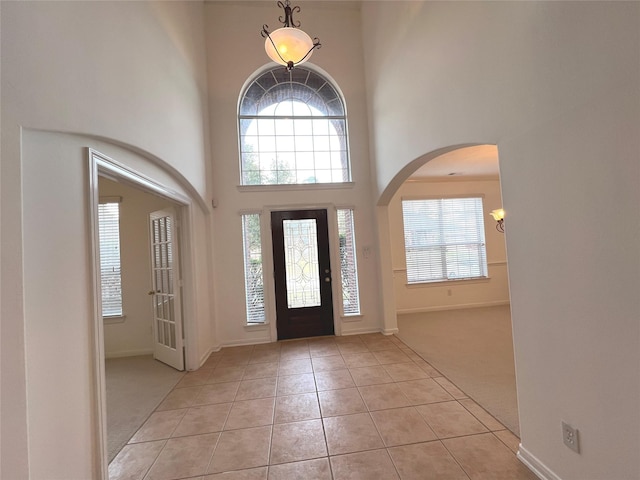 6731 Pinetop Glen Ln, Spring, TX 77379 - foyer featuring a towering ceiling, light carpet, arched walkways, light tile patterned flooring, and healthy amount of natural light