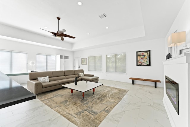 living room featuring ceiling fan and a tray ceiling