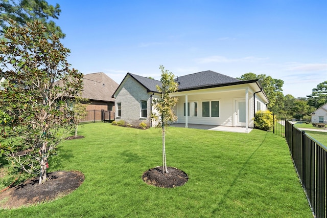 rear view of property with a yard and a patio