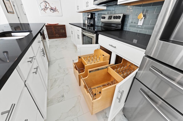 kitchen with refrigerator, stainless steel electric range, decorative backsplash, white cabinets, and sink