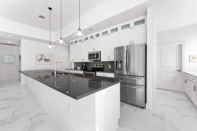 kitchen with stainless steel appliances, white cabinetry, and an island with sink