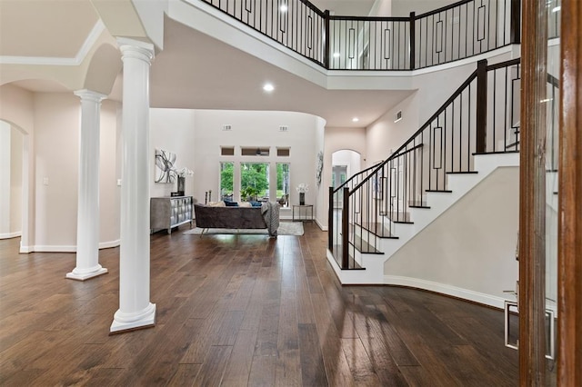 foyer entrance with hardwood / wood-style floors, a high ceiling, and ornate columns