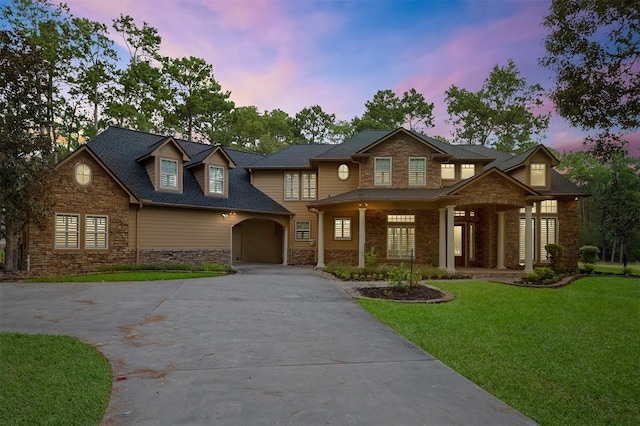 view of front of house with driveway, stone siding, and a front lawn