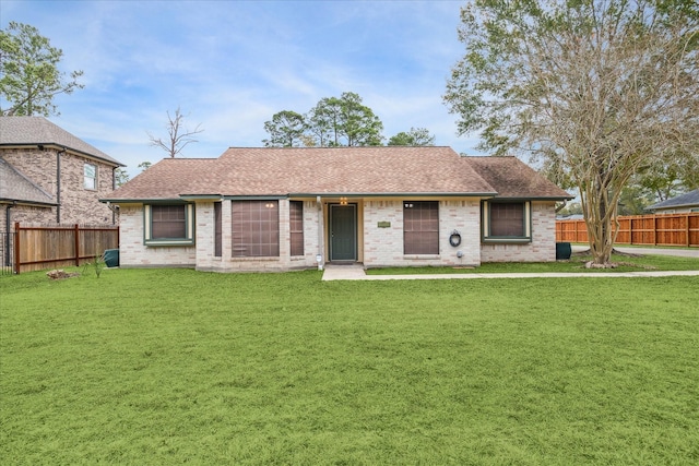 single story home featuring a front yard, roof with shingles, and fence