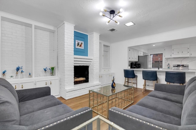 living room with a brick fireplace, hardwood / wood-style floors, and a textured ceiling