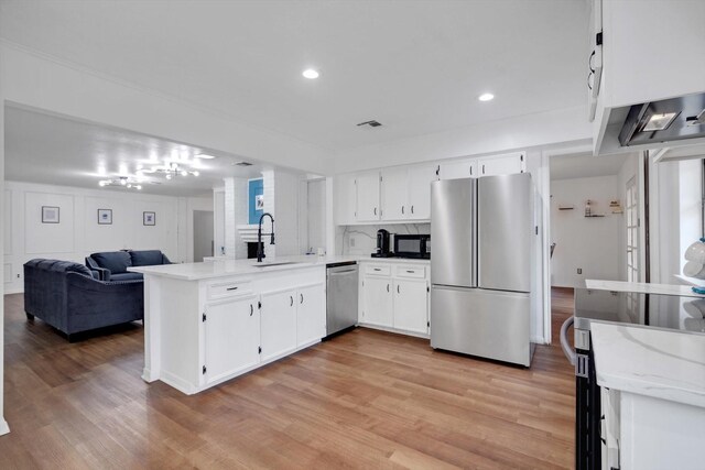 kitchen with kitchen peninsula, light hardwood / wood-style flooring, appliances with stainless steel finishes, sink, and white cabinets