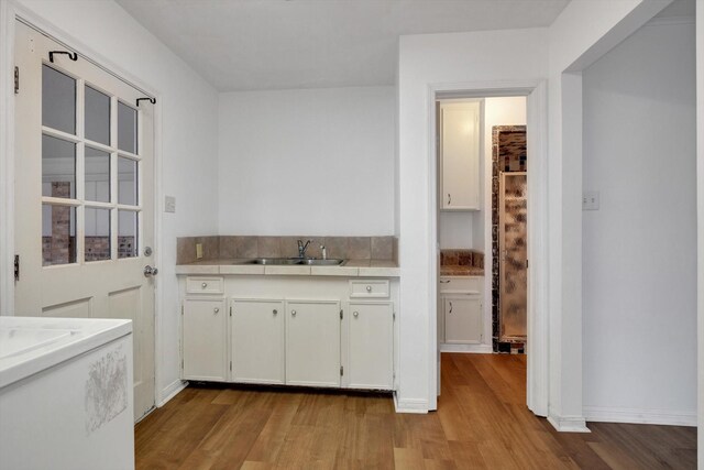 kitchen with sink, white cabinetry, and light hardwood / wood-style flooring