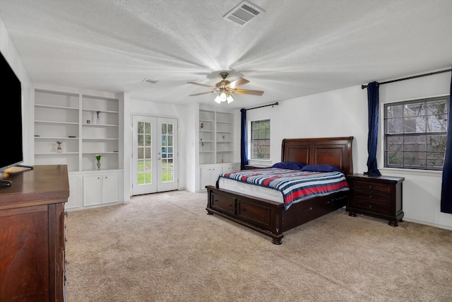 bedroom with light carpet, ceiling fan, french doors, and a textured ceiling