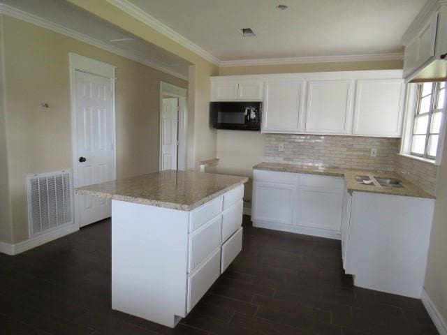 kitchen with a kitchen island, white cabinetry, and dark hardwood / wood-style flooring