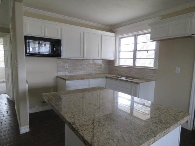 kitchen with dark hardwood / wood-style flooring, white cabinets, ornamental molding, a kitchen island, and decorative backsplash