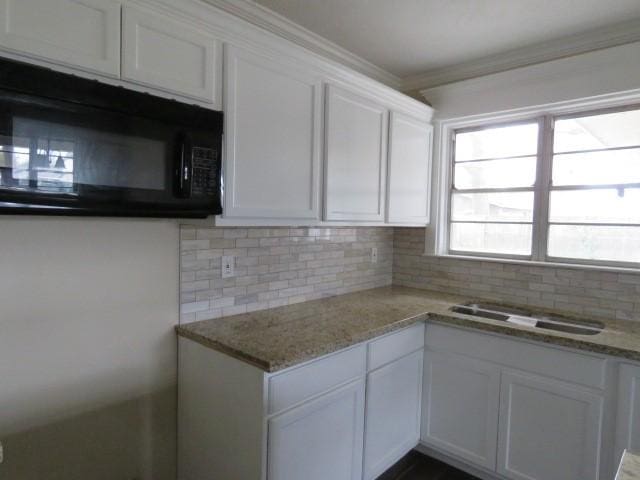 kitchen with white cabinetry, decorative backsplash, sink, light stone counters, and crown molding