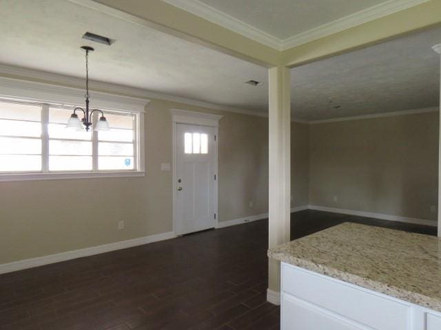 foyer with dark wood-type flooring, ornamental molding, and an inviting chandelier