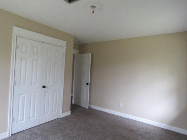 unfurnished bedroom featuring a closet and dark carpet