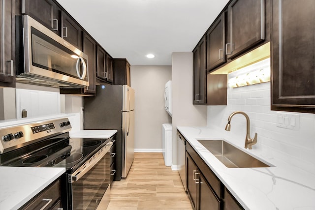 kitchen featuring light stone countertops, sink, light hardwood / wood-style flooring, separate washer and dryer, and stainless steel appliances