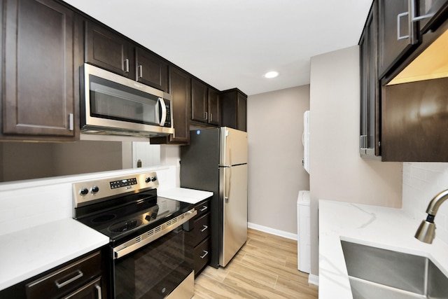 kitchen featuring sink, light hardwood / wood-style flooring, dark brown cabinetry, and appliances with stainless steel finishes