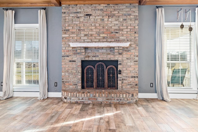 unfurnished living room featuring hardwood / wood-style flooring, beam ceiling, and a fireplace