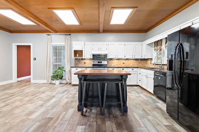 kitchen featuring white cabinets, black appliances, wood ceiling, a kitchen breakfast bar, and sink