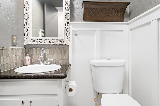 bathroom with toilet, vanity, and tasteful backsplash