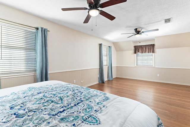 bedroom with lofted ceiling, multiple windows, ceiling fan, and light hardwood / wood-style floors