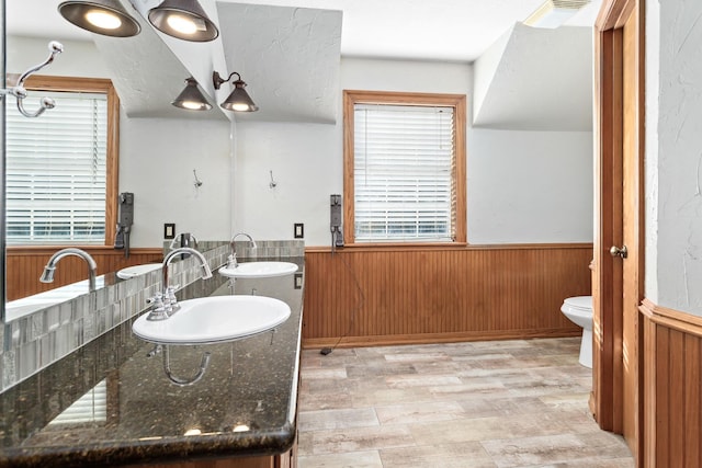 bathroom featuring wood-type flooring, wood walls, toilet, and vanity