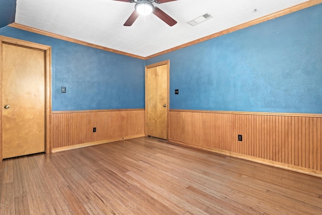 spare room with ceiling fan, ornamental molding, and light wood-type flooring