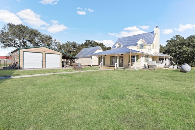 back of property featuring a garage, a lawn, an outdoor structure, and covered porch