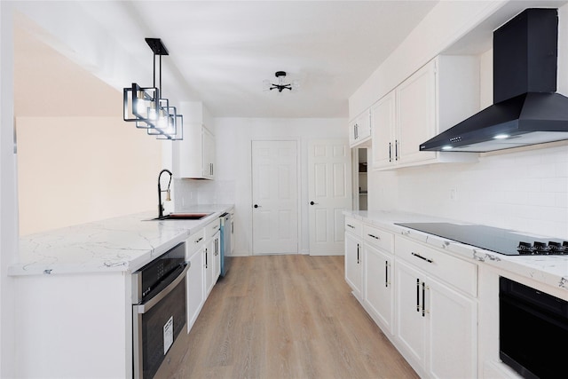 kitchen with white cabinetry, decorative light fixtures, wall chimney range hood, and appliances with stainless steel finishes