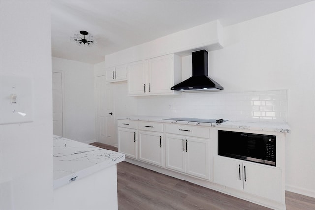 kitchen with light hardwood / wood-style floors, white cabinetry, black electric cooktop, and wall chimney exhaust hood