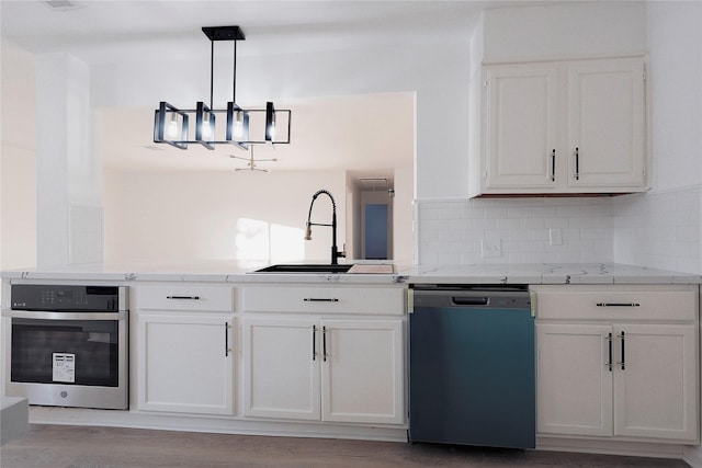 kitchen with appliances with stainless steel finishes, white cabinets, sink, backsplash, and hanging light fixtures