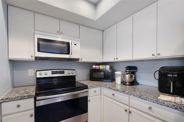 kitchen with light stone counters, white cabinetry, and stainless steel electric range