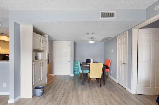 dining area featuring light hardwood / wood-style floors and a textured ceiling