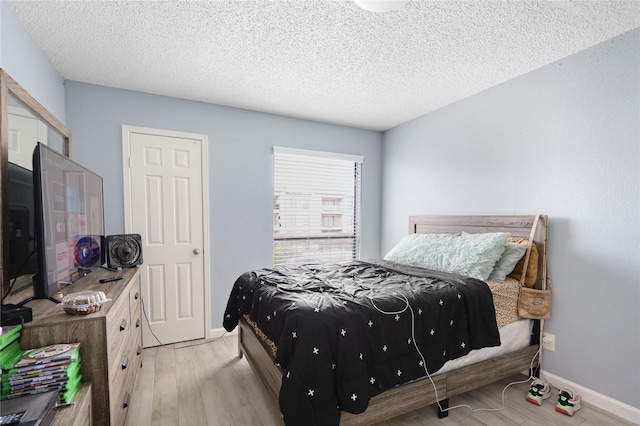 bedroom with light wood-type flooring and a textured ceiling