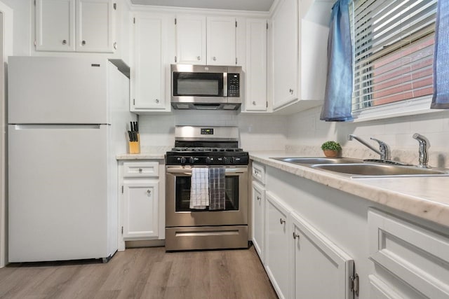 kitchen with light hardwood / wood-style flooring, sink, white cabinets, tasteful backsplash, and stainless steel appliances