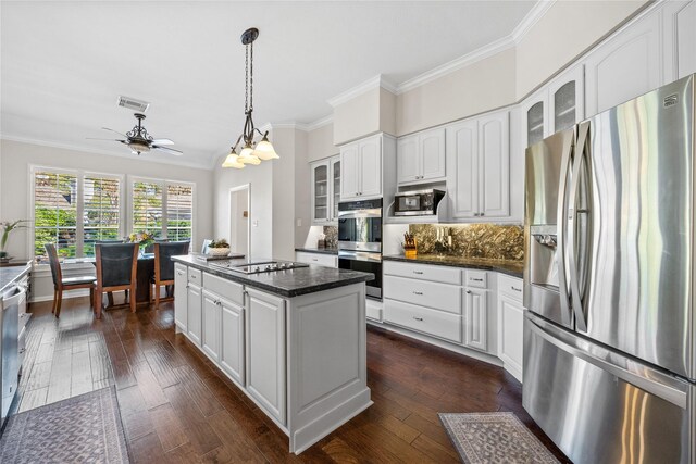 kitchen with a center island, stainless steel appliances, white cabinetry, and tasteful backsplash