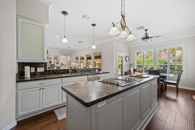 kitchen with white cabinets, dishwasher, a kitchen island, black cooktop, and crown molding