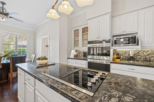 kitchen featuring stainless steel appliances, white cabinetry, hanging light fixtures, and ornamental molding