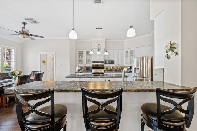 kitchen with a kitchen breakfast bar, white cabinetry, ornamental molding, and stainless steel appliances